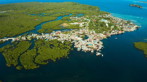 Town in wetlands and mangroves on the ocean coastline from above. Siargao island, Philippines.