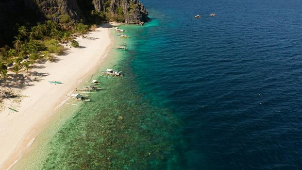 aerial view island with tropical sandy beach and palm trees. Malajon Island, Philippines, Palawan. tourist boats on coast tropical island. Summer and travel vacation concept. beach and blue clear sea water