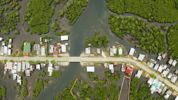 Highway through the mangrove forest passing through the village, aerial view. Siargao island, Philippines.