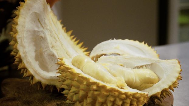 hand peeling and cuts durian fruit. caucasian man peeling durian in kitchen room