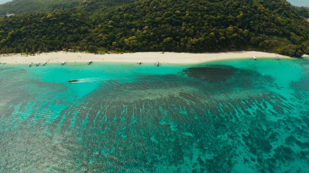 Tropical white sand beach, near the blue lagoon and corall reef from above, Boracay, Philippines. Sandy beach with tourists. Summer and travel vacation concept.