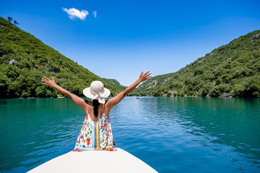 cliffy rocks of Verdon Gorge at lake of Sainte Croix, Provence, France, Provence Alpes Cote d Azur, blue green lake with boats in France Provence. Europe, young woman in peddle boat looking at river