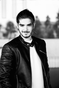 Half length portrait of handsome bearded man dressed in fashionable clothes standing on street against while wall background with area for advertising content.Handsome hipster guy posing on copy space