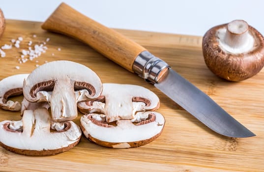 Royal champignons, Parisian champignons, mushrooms on bamboo wooden chopping board. Dark wooden background. Side view.