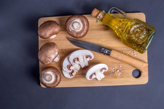Still life of mushrooms, Royal champignons on a cutting board with knife and a bottle with olive oil,top view