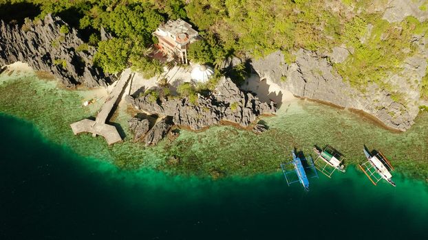 Tropical landscape bay with beach and clear blue water surrounded by cliffs, aerial drone. El nido, Philippines, Palawan. Seascape with tropical rocky islands, ocean blue water. Summer and travel vacation concept