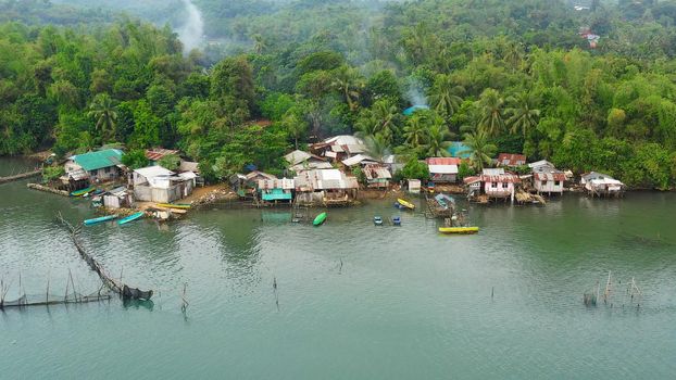 Fishing village with wooden houses standing on stilts in the sea from above. Houses community standing in water in fishing village. Luzon, Philippines.