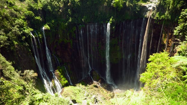 waterfall Coban Sewu in tropical forest, Java Indonesia. tumpak sewu waterfall in rainforest aerial footage