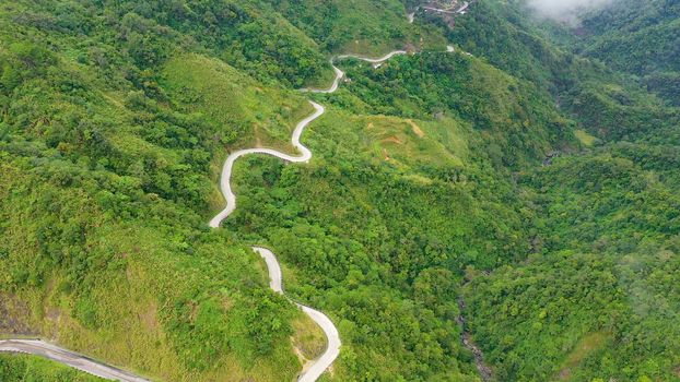 Fragment of a high altitude road in the mountains. Mountains covered by rainforest, aerial view. Cordillera on Luzon Island, Philippines.