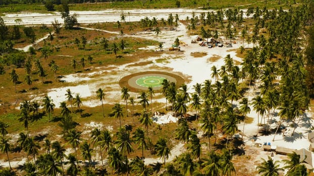 Helipad among the palm trees on a tropical island top view. Helicopter landing site. Bugsuk island, Balabac, Palawan