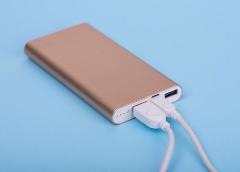 Smartphone charging with power bank on a blue background.