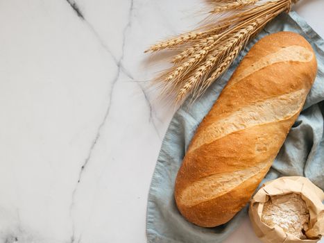 British White Bloomer or European Baton loaf bread on white marble background. Top view or flat lay. Copy space for text or design.