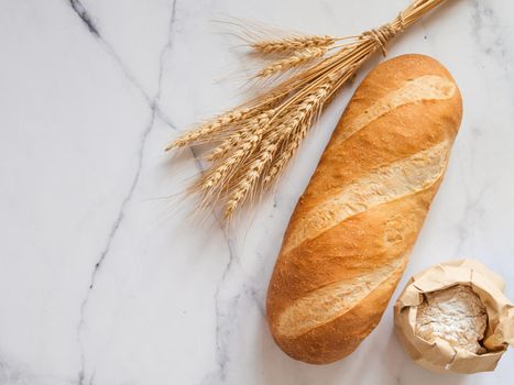 British White Bloomer or European Baton loaf bread on white marble background. Top view or flat lay. Copy space for text or design.