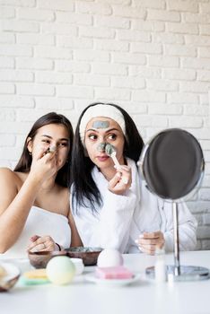 Spa and wellness concept. Self care. two beautiful women applying facial mask having fun