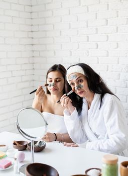 Spa and wellness concept. Self care. two beautiful women applying facial mask having fun