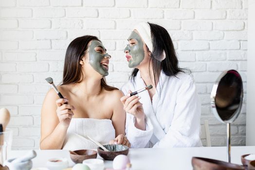 Spa and wellness concept. Self care. two beautiful women applying facial mask having fun