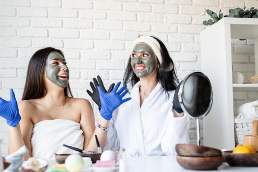 Spa and wellness concept. Self care. Two beautiful women in gloves applying facial mask having fun