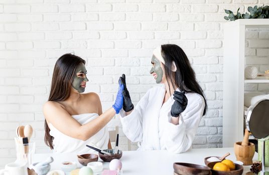 Spa and wellness concept. Self care. Two beautiful women in gloves applying facial mask having fun