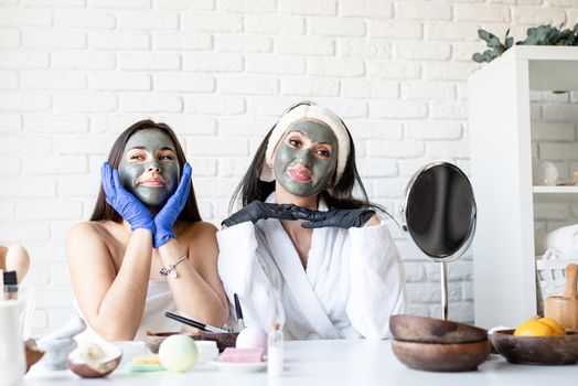 Spa and wellness concept. Self care. Two beautiful women in gloves applying facial mask having fun