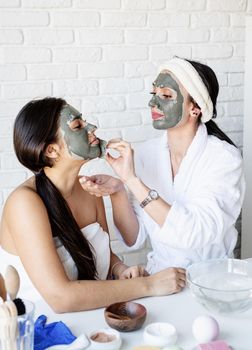 Spa and wellness concept. Self care. two beautiful women in bath robes applying facial mask having fun
