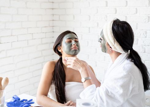 Spa and wellness concept. Self care. two beautiful women in bath robes applying facial mask having fun