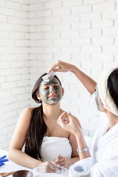 Spa and wellness concept. Self care. two beautiful women in bath robes applying facial mask having fun