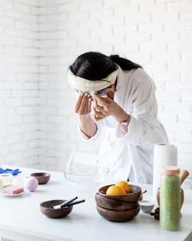 Spa and wellness concept. Self care. Portrait of a woman in white bath robes making facial mask doing spa procedures