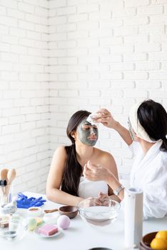 Spa and wellness concept. Self care. two beautiful women in bath robes applying facial mask having fun