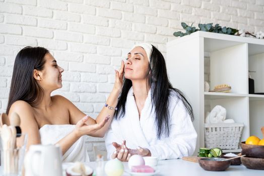 Spa and wellness concept. Self care. two beautiful women applying facial cream doing spa procedures