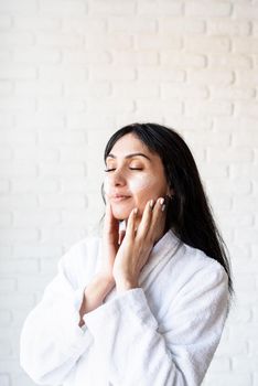 Spa and beauty. Happy beautiful middle eastern woman wearing bath towels applying facial cream on her face