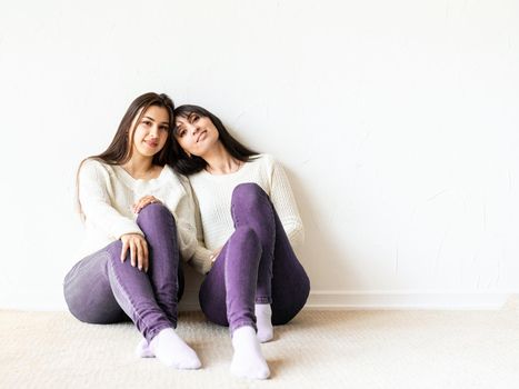 Two female best friends in casual clothes sitting together at home. Copy space