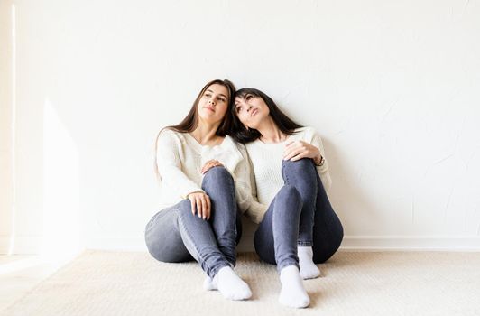 Two female best friends in casual clothes sitting together at home. Copy space