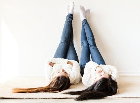 Friendship. Two women laying at the rug legs up having fun