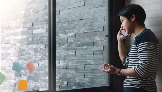 Cheerful male freelancer making telephone call about business project working in office