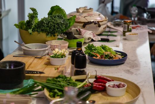 A kitchen with a cooking table in the middle of the room and the table is full of ingredients for cooking. The concept of a food healthy lifestyle. No focus, specifically.