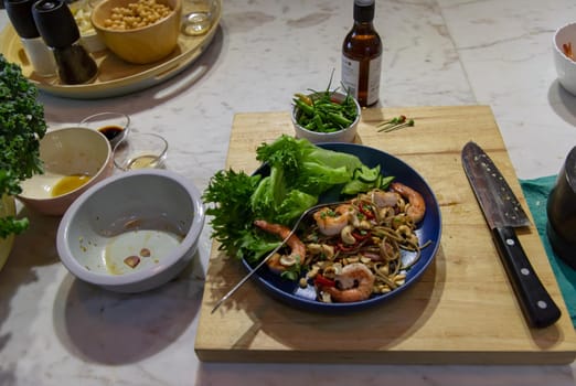Udon and prawn spicy salad plate on wooden cutting board. Selective focus.