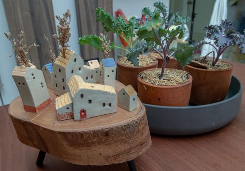 Many little houses made in wood and Kale vegetables tree planted growing in four ceramic plant pot for house decoration. Selective focus.