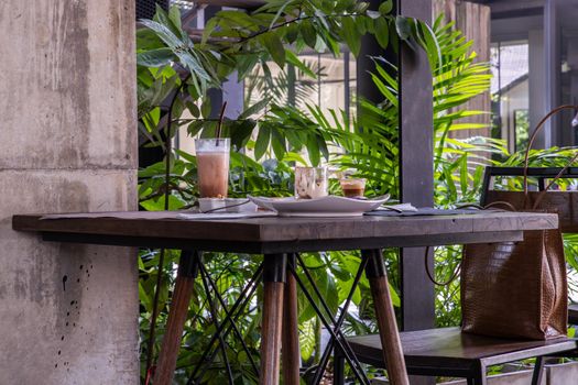 Bakery and iced coffee on wooden table with green garden background. Food and Drink, Copy space, Selective focus.