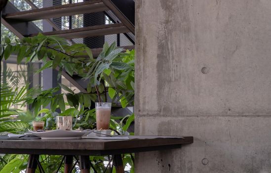 Bakery and iced coffee on wooden table with green garden background. Food and Drink, Copy space, Selective focus.