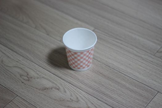 Paper, cardboard disposable glass on a wooden floor. Disposable paper cups on the wooden floor