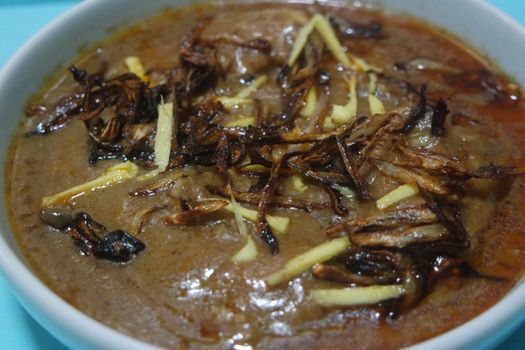 Closeup view of traditional Pakistani Haleem dish with salad and Lemon juice.