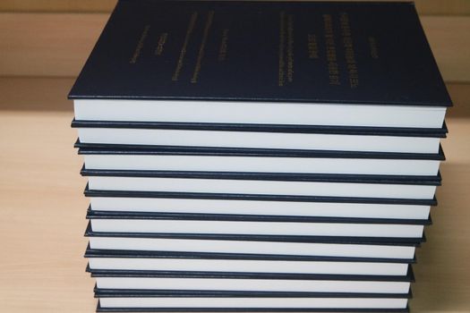 Stack of blue books placed on table. Thesis books with golden words on blue hardcover