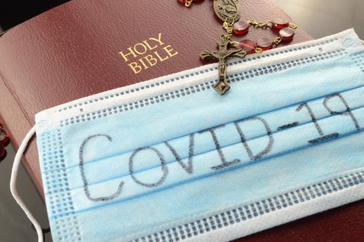 A closeup of a bible and a Covid mask to send a prayer for support.