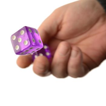 A concept of risk involvement with a hand and a roll of the dice over a white background.