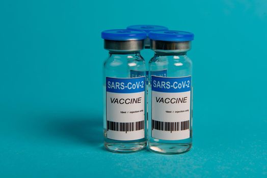 Covid-19 coronavirus vaccine bottle on blue background. Selective focus.