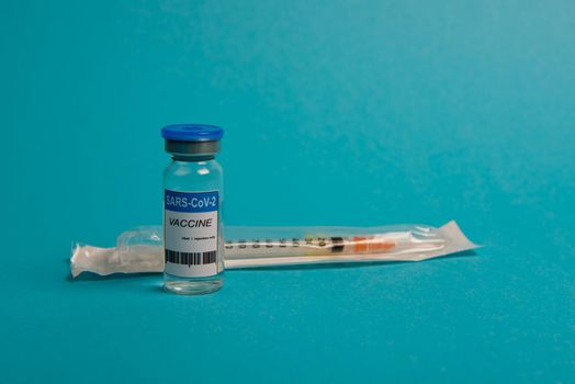 Covid-19 coronavirus vaccine bottle and syringe on blue background. Selective focus.