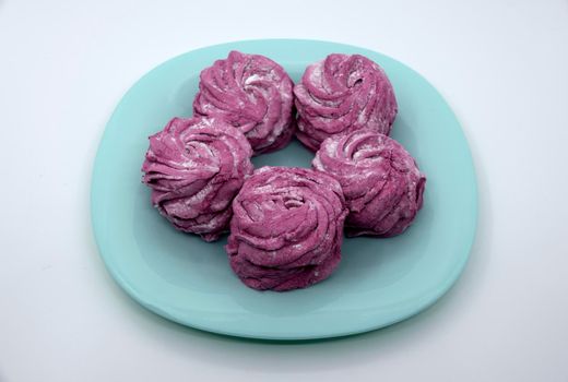 Bright appetizing raspberry marshmallow on a turquoise saucer.