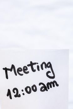 Meeting handwriting text close up isolated on white paper with copy space. Writing text on memo post reminder