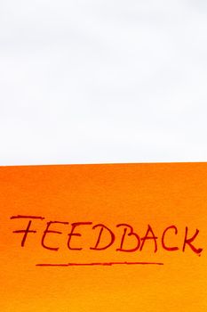 Feedback handwriting text close up isolated on orange paper with copy space.