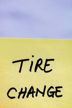Tire change handwriting text close up isolated on yellow paper with copy space.